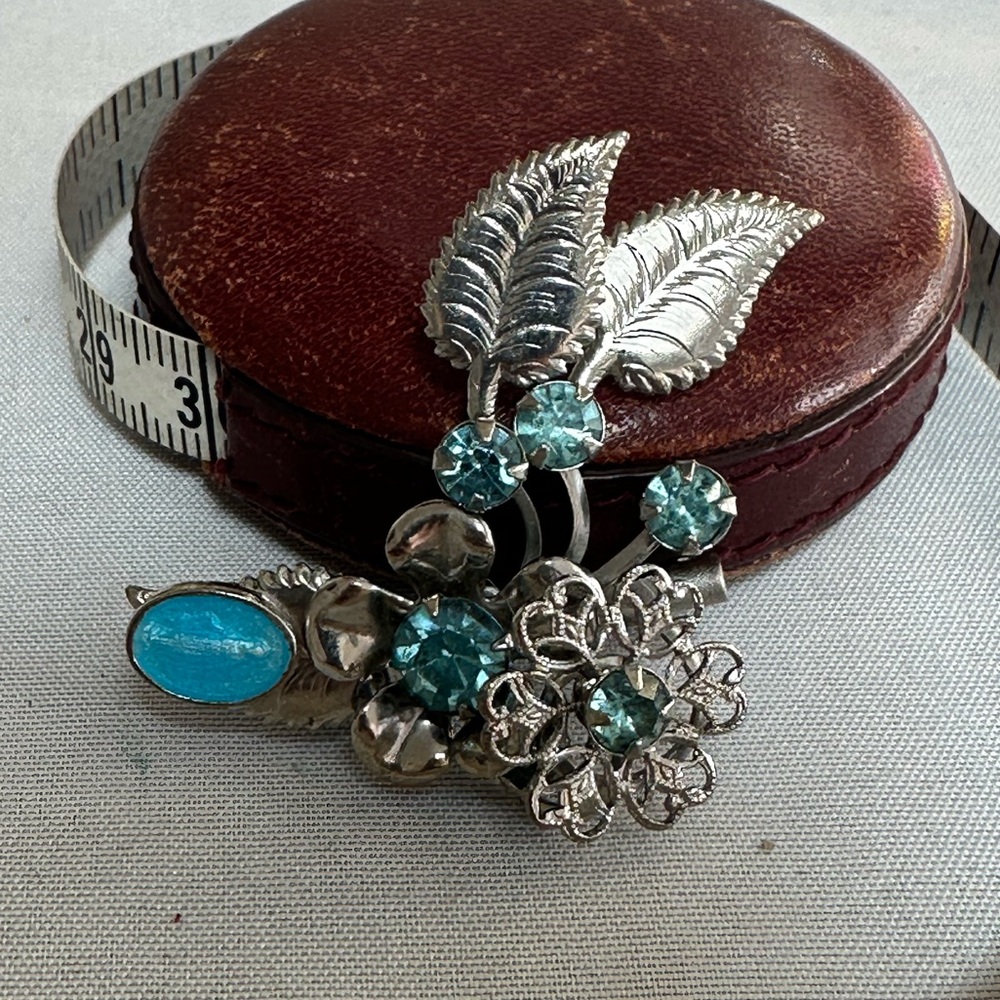 Small silvertone floral pin with blue rhinestones